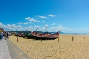 a row of boats sitting on top of a sandy beach