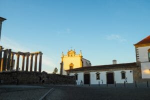 a building with columns and a clock tower in the background