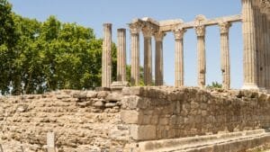 a stone wall with columns and trees in the background