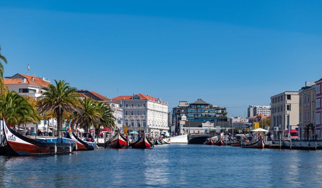 Aveiro, Portugal - 15 October, 2021: Traditional colorful houses and boats on the canal in Aveiro, Portugal. Beautiful sunny day with blue sky.
