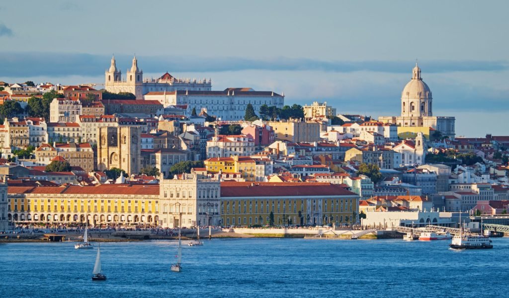 View of Lisbon Alfama district with National Pantheon and Monastery of St. Vincent over Tagus river from Almada with yachts tourist boats on sunset. Lisbon, Portugal